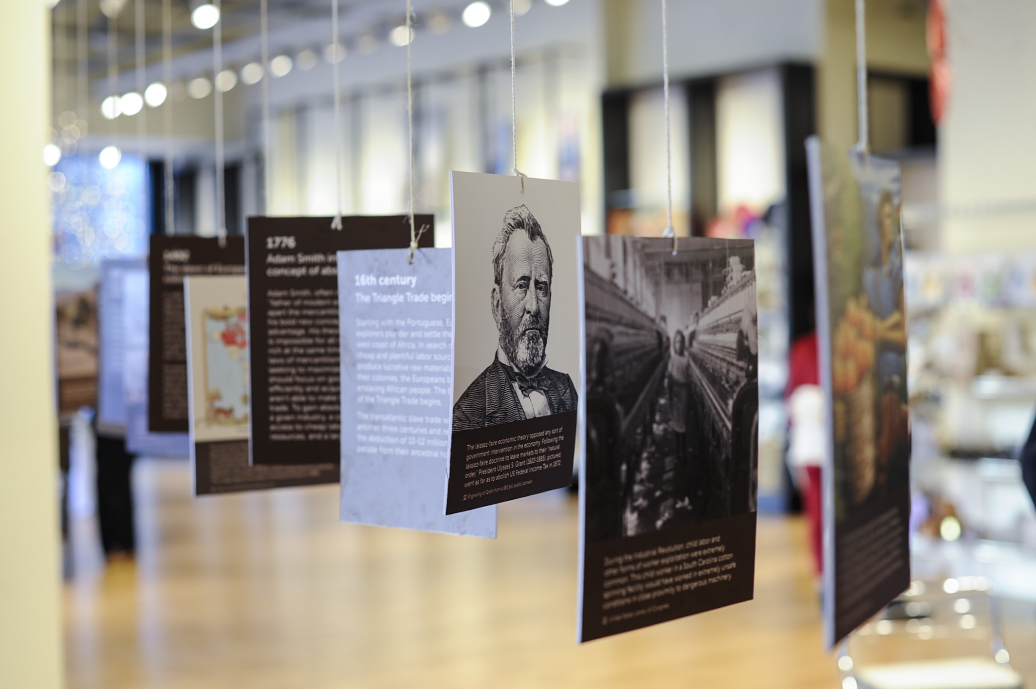 Exhibit cards hanging from strings in the Chicago Fair Trade Museum.