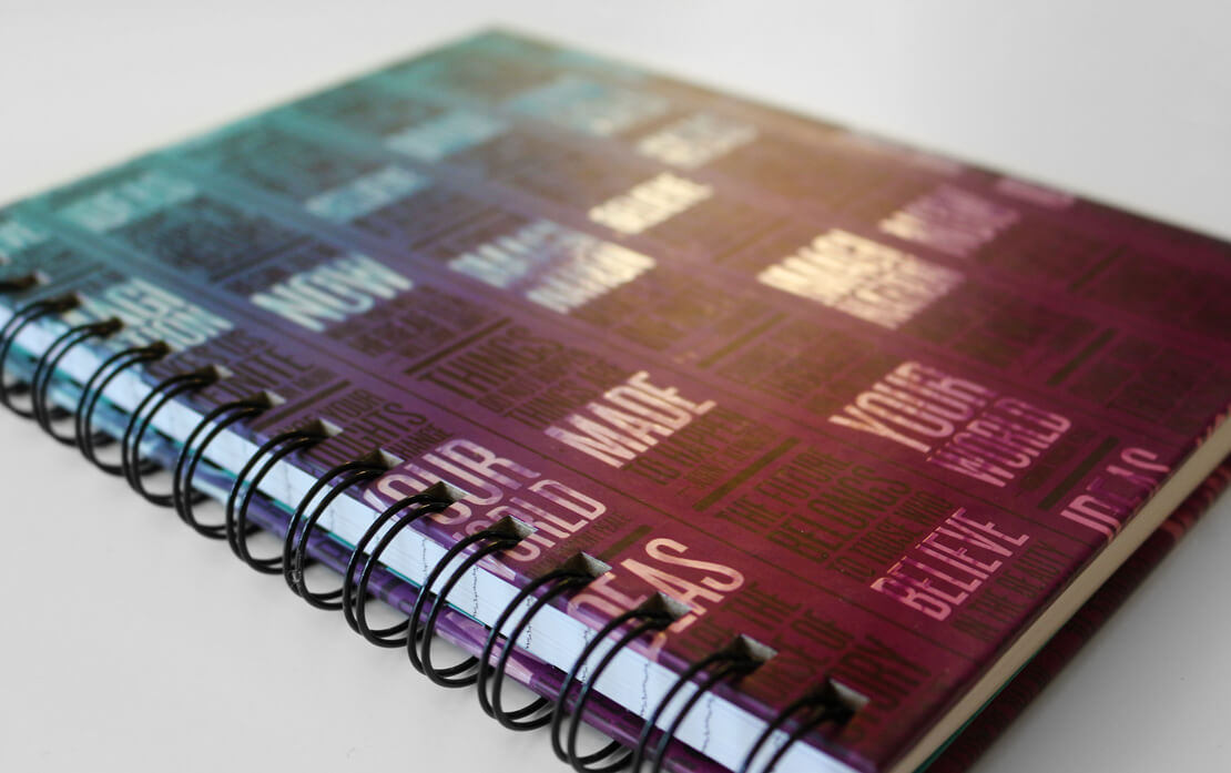 The interior of the notebook features a robin's egg blue endpaper with a large John Muir quote in a narrow column. On the other side of the spread, lined paper is visible for writing. A Copic marker and felt tip pen are scattered above the notebook.