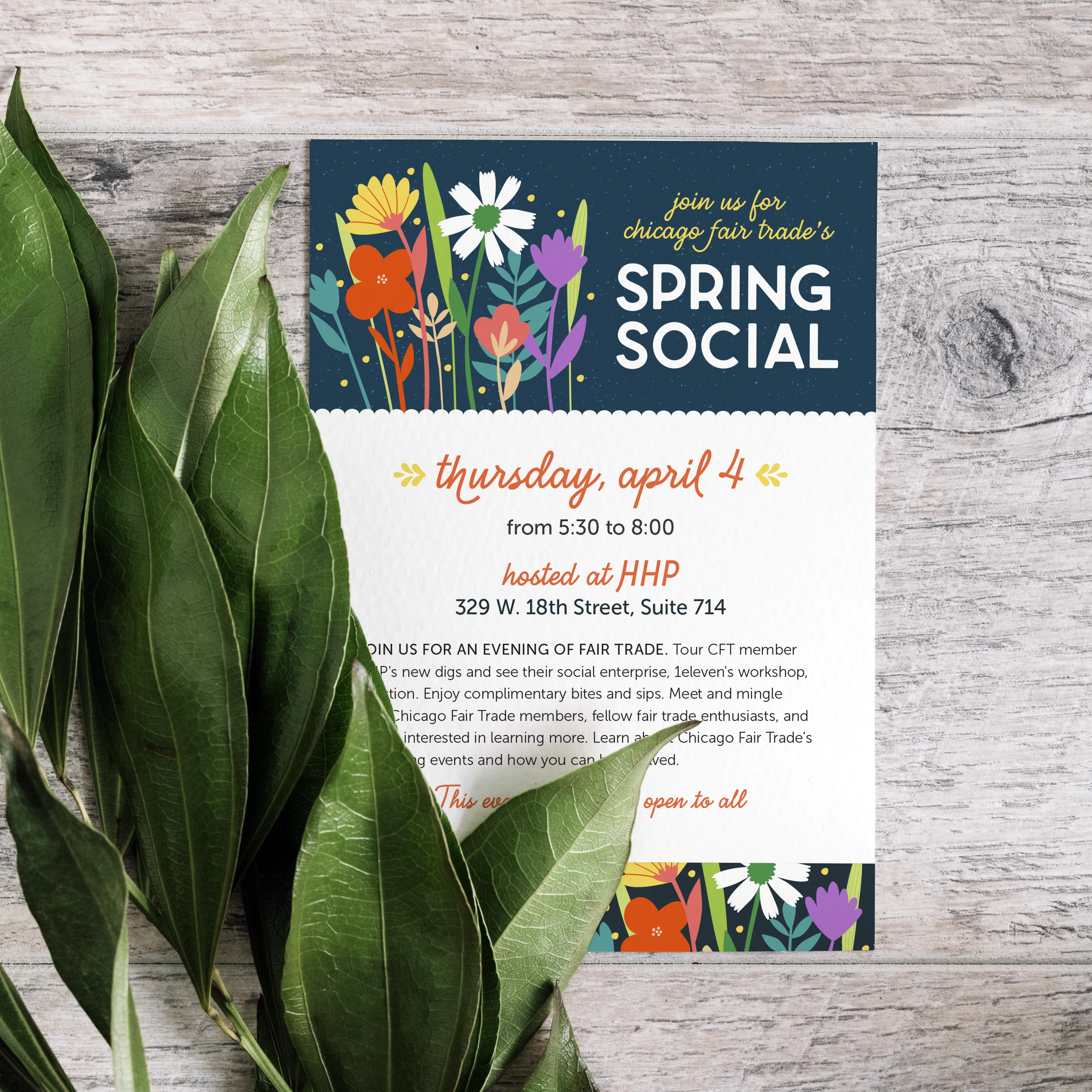 A colorful event invitation for 'Chicago Fair Trade's Spring Social' resting on a light wood surface next to several green leaves. The top of the card features a vibrant teal header filled with stylized, flat-illustration spring flowers in bold colors, including Chicago Fair Trade's brand colors. The title 'Spring Social' is set in a bold, clean white sans-serif font. Below, the event details are displayed on a white background with a decorative scalloped edge. The date is written in an elegant, burnt-orange cursive script and surrounded by goldenrod decorative elements, while other details are presented in a modern, minimalist font. Small floral motifs at the bottom mirror the header design.