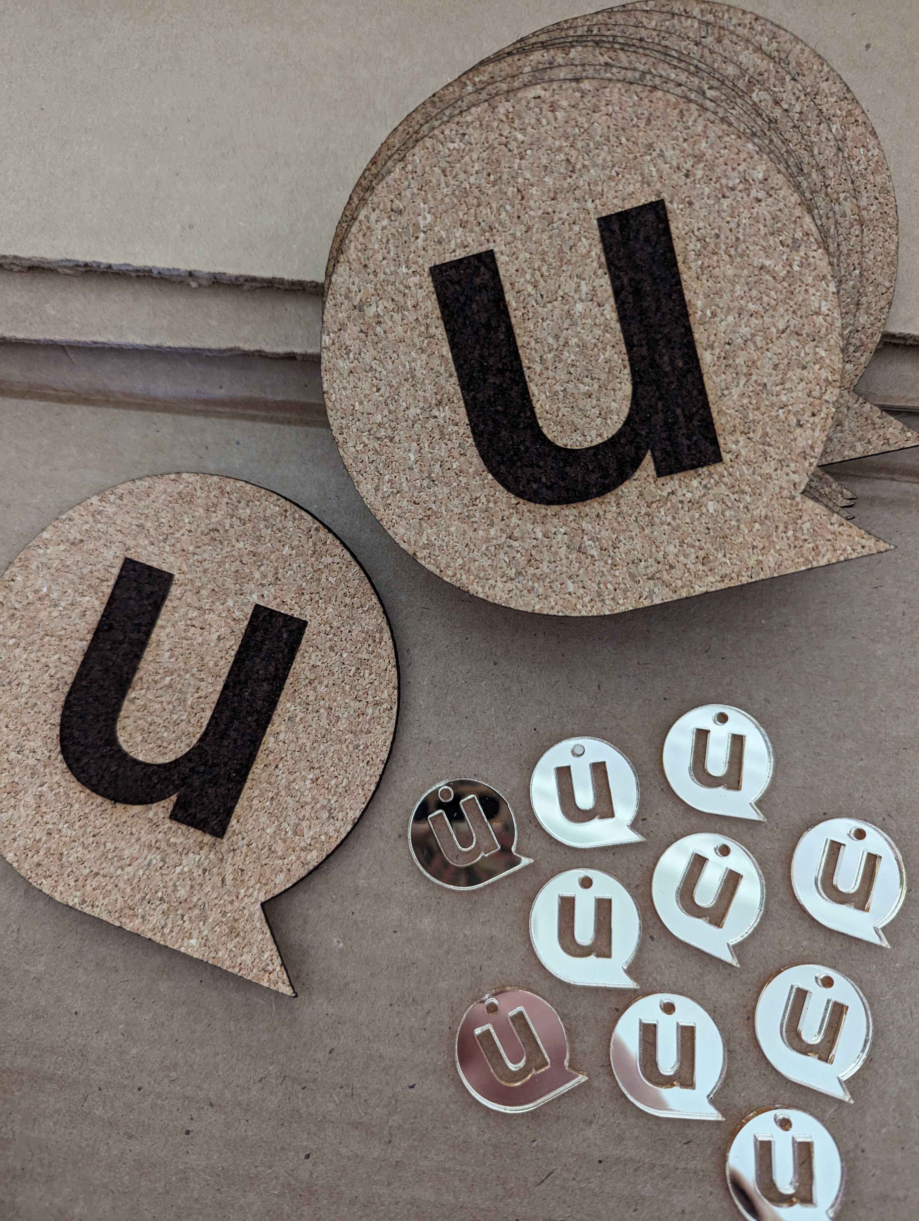 Laser-cut cork coasters shaped like the uConnect icon. Various unassembled earring charms are also visible.